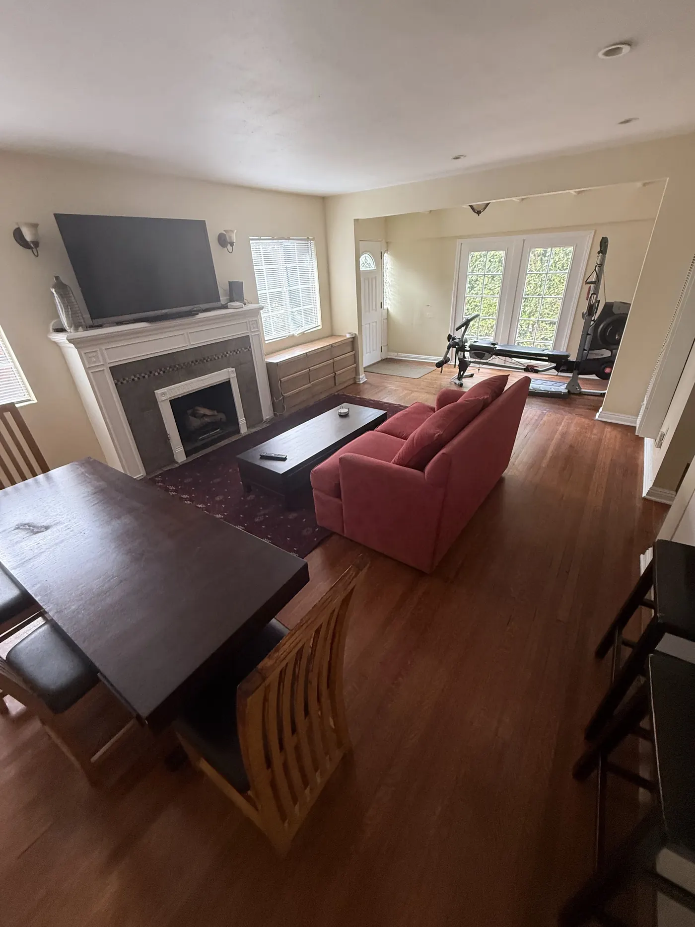 Shared living and dining room with sofa, TV, fireplace, and exercise area